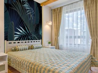 Ściana za łóżkiem w sypialni wykończona tapetą z motywem roślinnym
